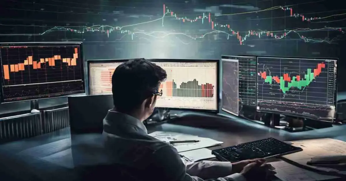 Trader analyzing financial charts on multiple screens.